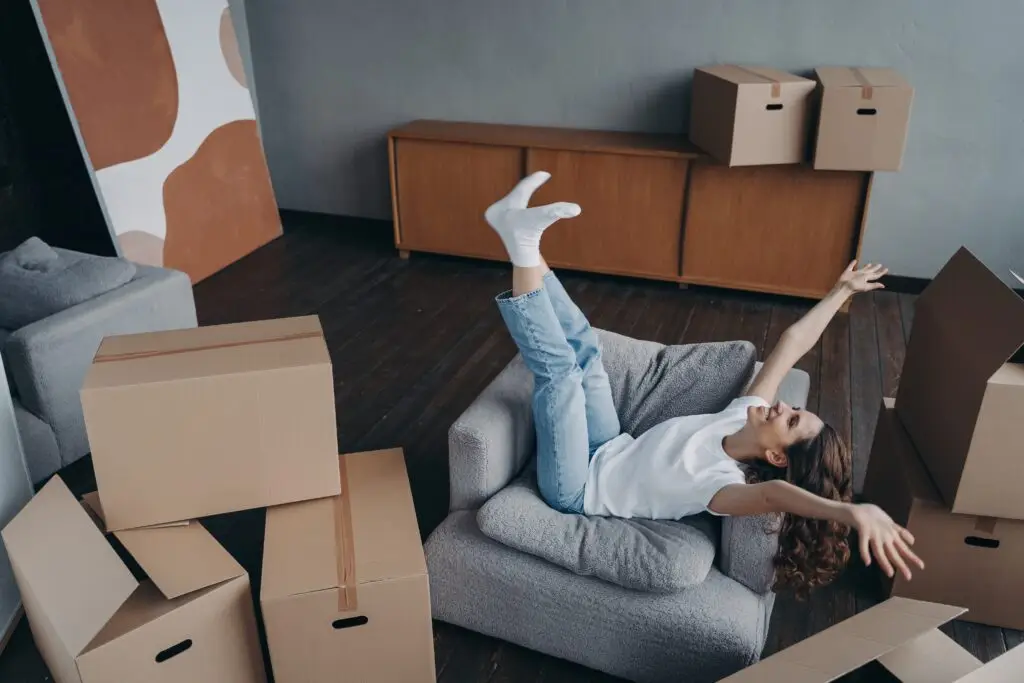 excited woman celebrates relocation to new home, rejoicing surrounded by carton boxes on moving day